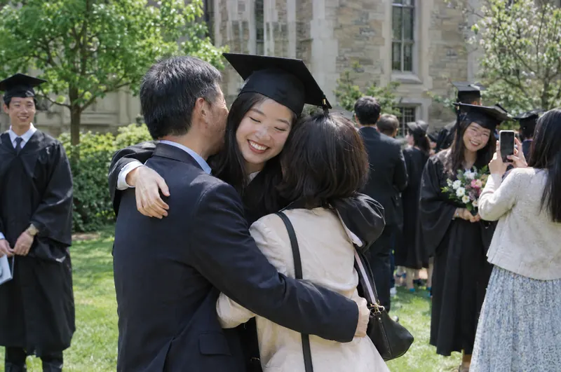 A university graduate hugging her parents after graduation