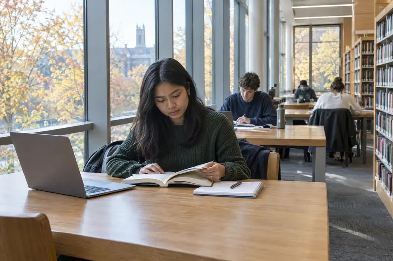 A student reading in a bright university library